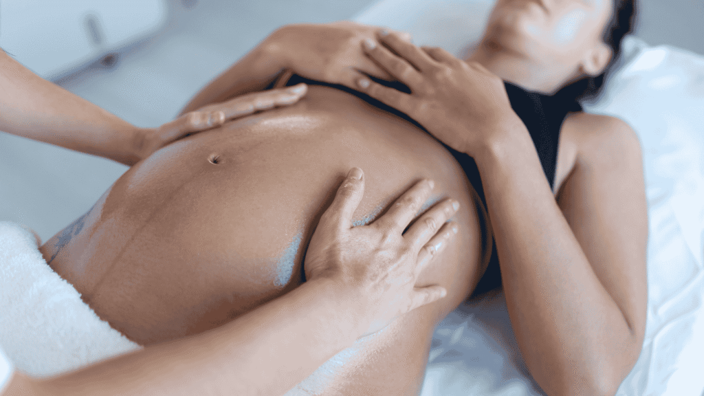 Séance d’ostéopathie pour femme enceinte en Haute-Garonne : mains d’une ostéopathe posées sur le ventre arrondi d’une future maman allongée
